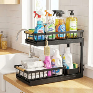 Two-tier sliding drawer under-sink organizer on a kitchen countertop holding cleaning bottles and dish soap.