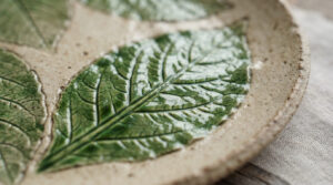 Close-up of the glossy three-dimensional cabbage leaf texture and detailed veining on a green stoneware ceramic plate.