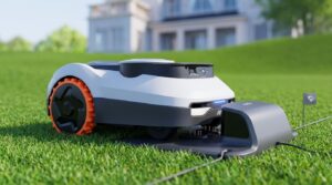 Segway Navimow i105E robotic lawn mower docked at its charging station on a manicured green lawn.