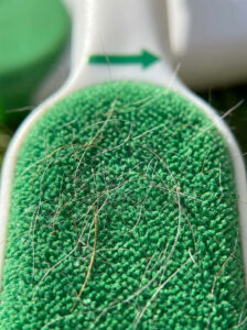 Close-up of the Fur Magic double-sided brush head showing micro-bristle directional velvet fabric collecting loose pet hair.
