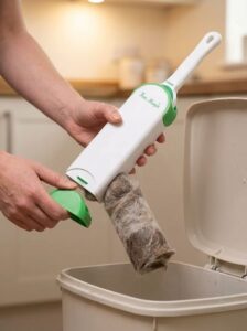 Person removing the bottom cap of the Fur Magic self-cleaning base to empty a rolled cylinder of collected pet fur into a bin.