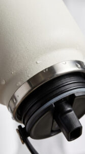 Close-up of a Hydro Flask bottle showing its durable powder-coat finish, stainless steel rim, and leakproof straw lid mechanism.